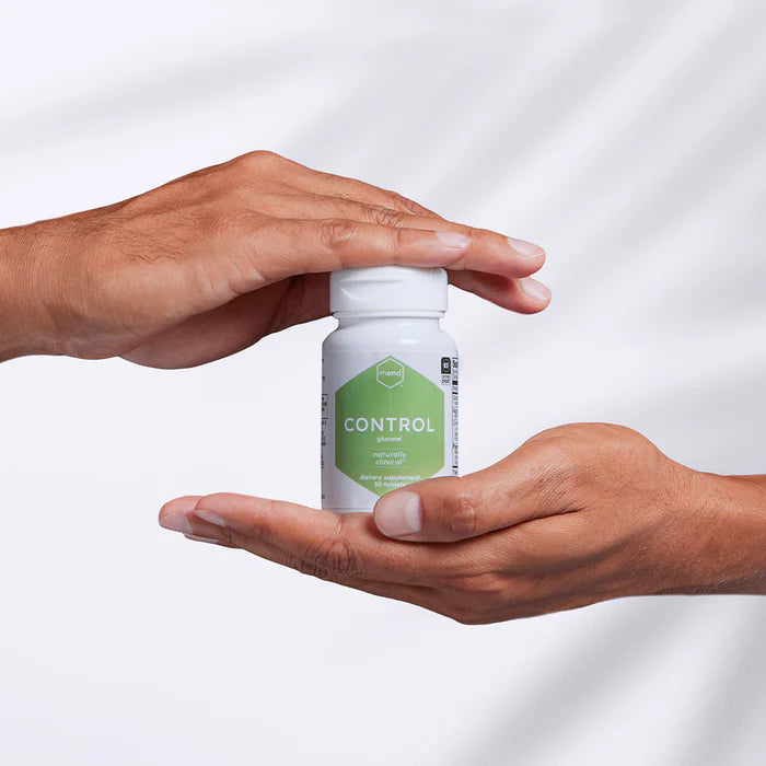 Dietary supplement bottle labeled Mend Control Glucose held between two hands against a white background