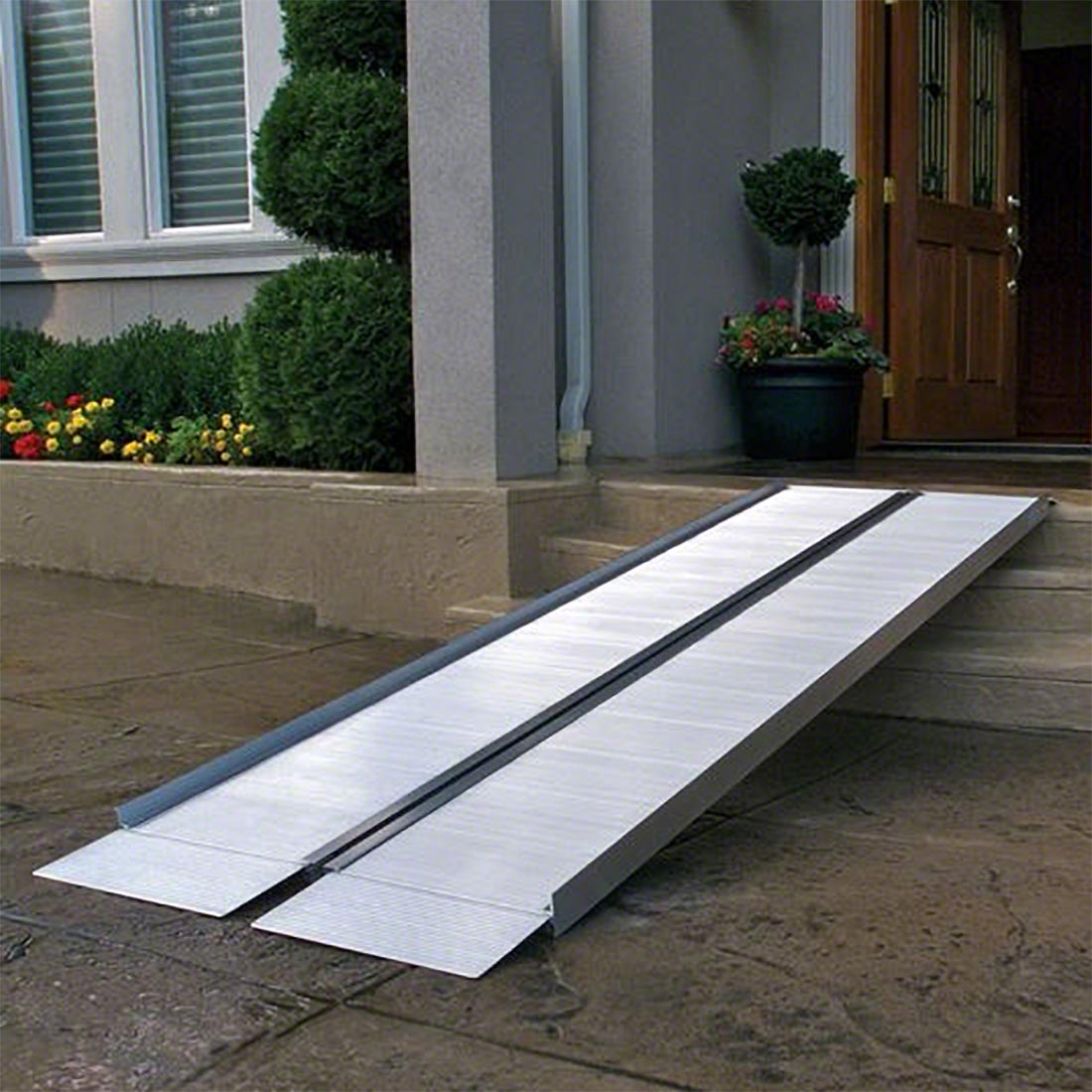 Folding aluminum wheelchair ramp positioned on outdoor steps leading to a residential front entrance