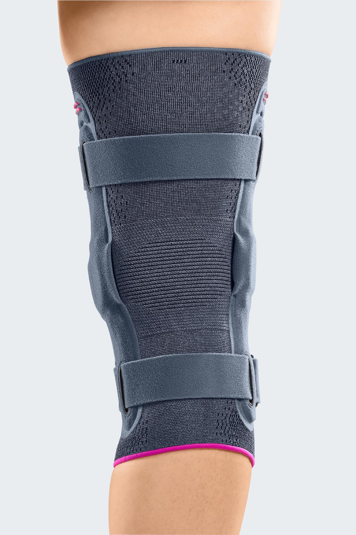 Knee brace with gray knit fabric, bilateral hinged stays, two adjustable straps, and pink trim accent, worn on leg