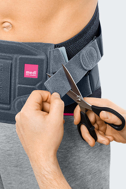 Lumbamed Facet lumbar support being trimmed to size with scissors at the waist strap closure