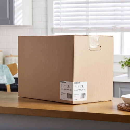 Disposable underpad bulk case in sealed cardboard shipping box with McKesson label, sitting on a kitchen counter