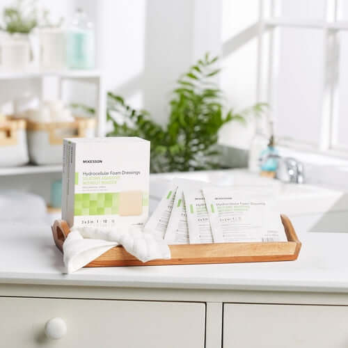 Foam wound dressings box with individually wrapped packets displayed on a wooden tray in a bright bathroom setting