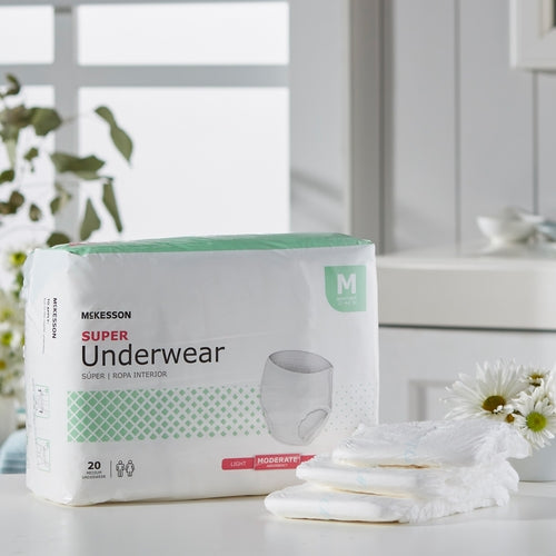 McKesson Super Underwear package in medium size displayed beside unfolded briefs and white flowers on a counter