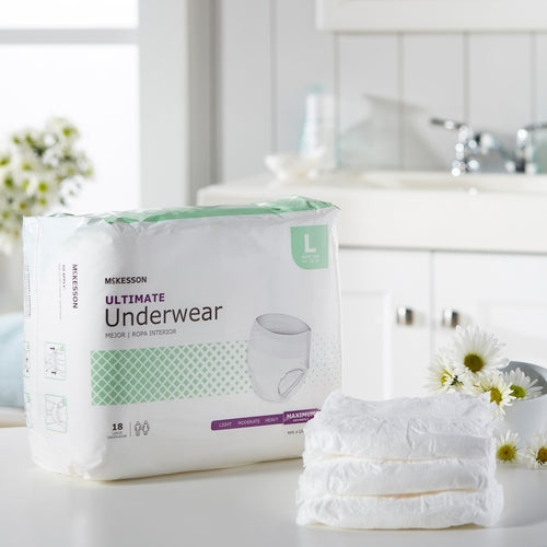 McKesson Ultimate Underwear package in Large size beside a folded stack of white briefs on a bathroom counter with daisies