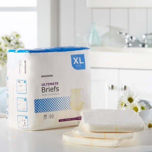 McKesson Ultimate Briefs XL incontinence brief package of 15 beside two unfolded briefs on a white countertop