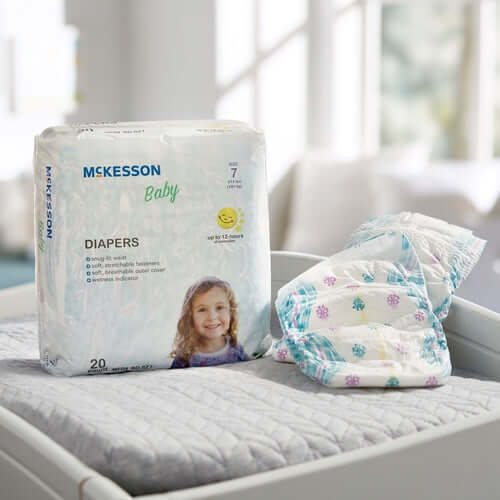 McKesson Baby Diapers size 7 package of 20 beside two unfolded diapers on a changing table surface
