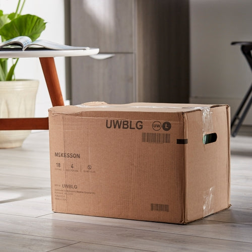 McKesson absorbent underwear in sealed cardboard shipping box on hardwood floor near a table and houseplant