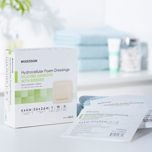 McKesson hydrocellular foam dressing box with silicone adhesive border beside individual sealed packet on white surface