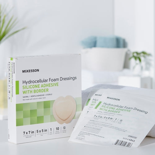 McKesson hydrocellular foam dressing box with silicone adhesive border beside two individual sealed dressing packets on