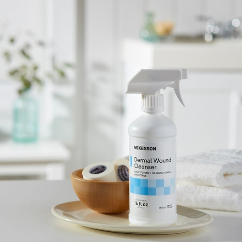 McKesson Dermal Wound Cleanser 16 oz spray bottle on a white tray beside a wooden bowl with gauze rolls in a bright bathroom