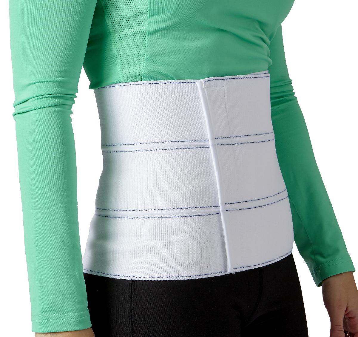 Abdominal binder in white elastic fabric with three panels and hook-and-loop closure, worn around a person's midsection