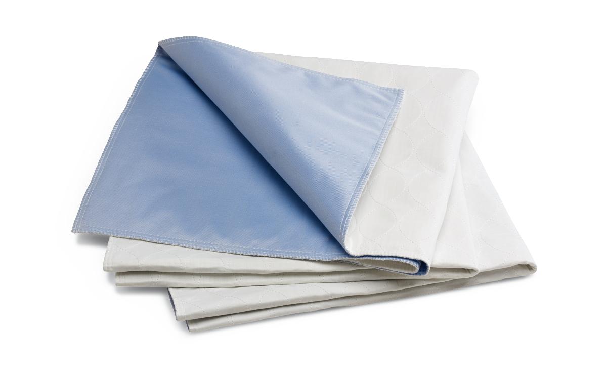 Reusable bed underpads folded in a stack, showing blue waterproof backing and white quilted top surface
