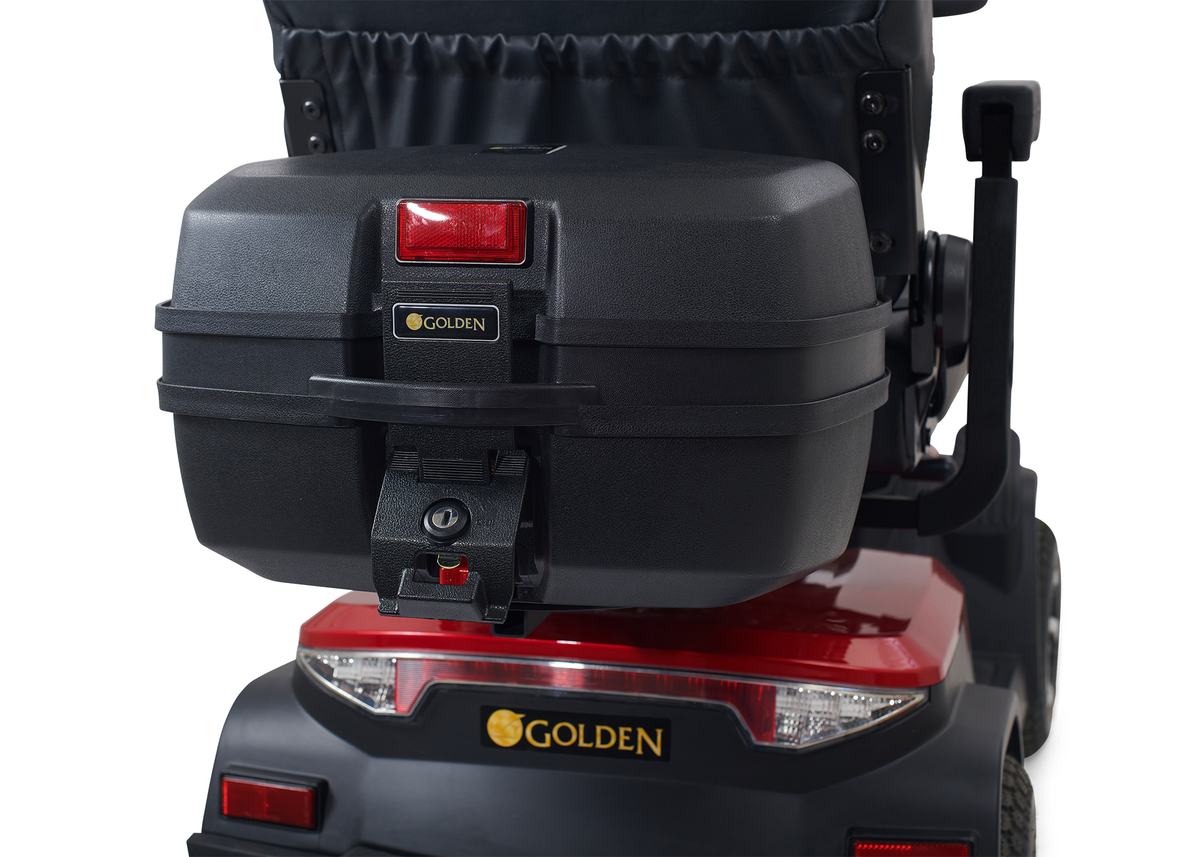 Golden mobility scooter rear view showing black locking storage trunk mounted behind the seat with red reflector