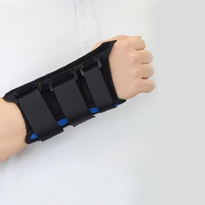 Wrist brace with black fabric, three hook-and-loop straps, and blue trim worn on a right hand and forearm