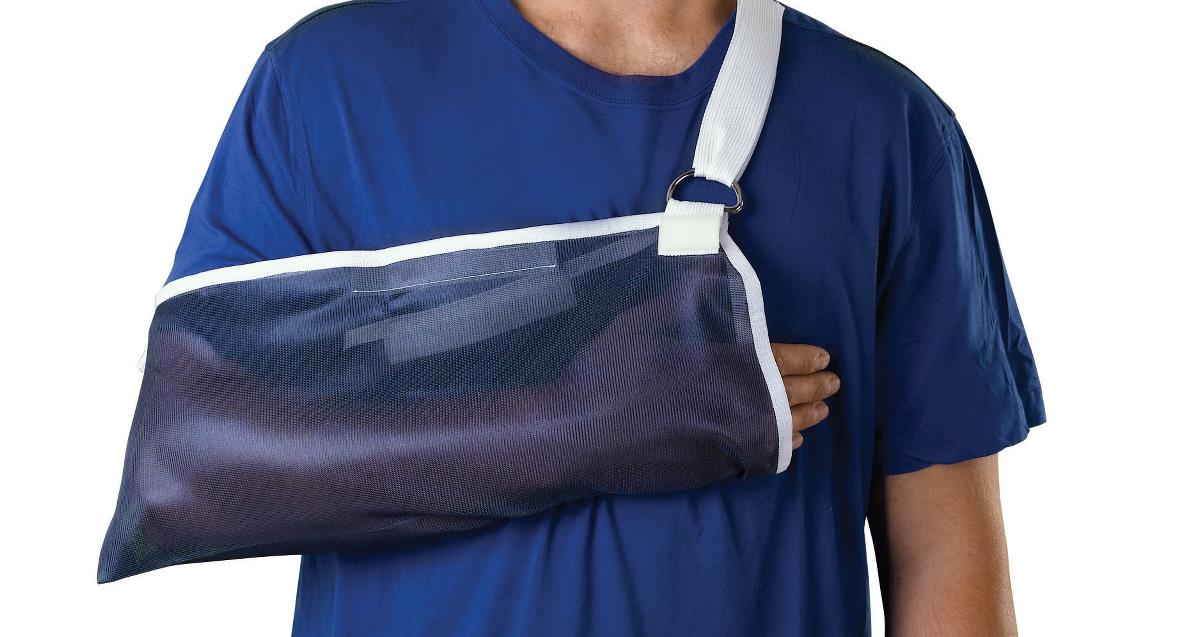 Universal arm sling in navy mesh with white adjustable strap, worn by person in blue t-shirt against white background