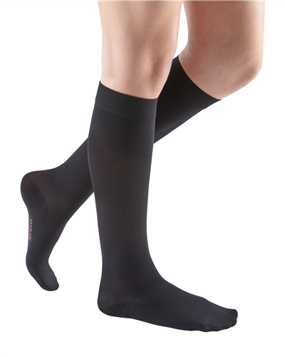 Compression socks in black worn on female legs, knee-high closed-toe style with smooth sheer finish