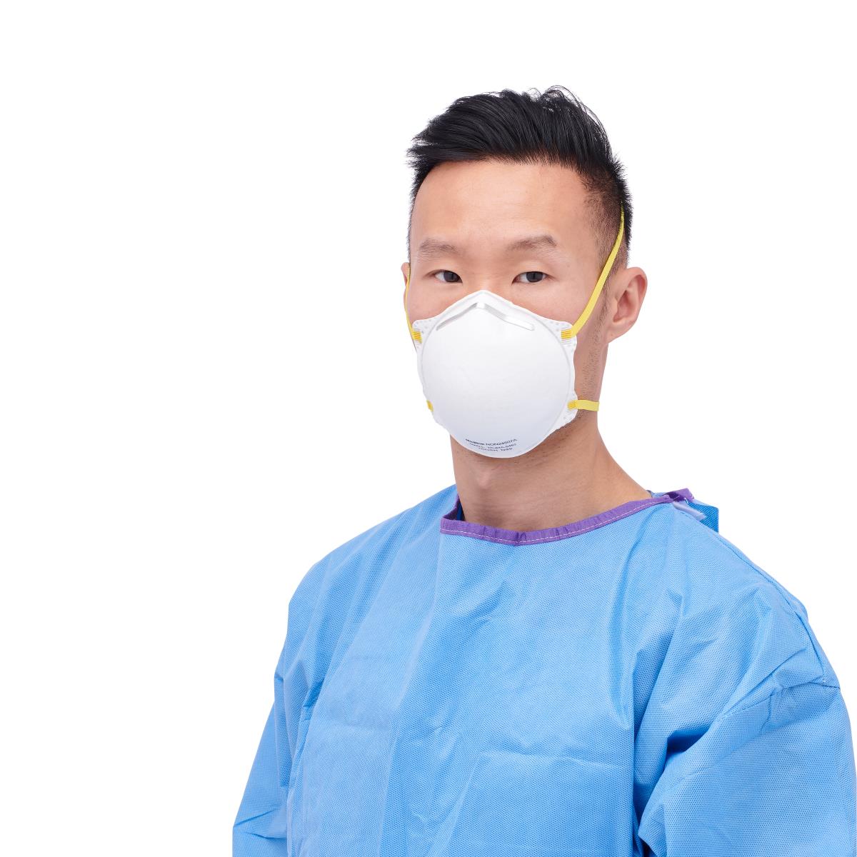 N95 cone-style respirator mask with yellow straps worn by a man in a blue isolation gown, front view on white background