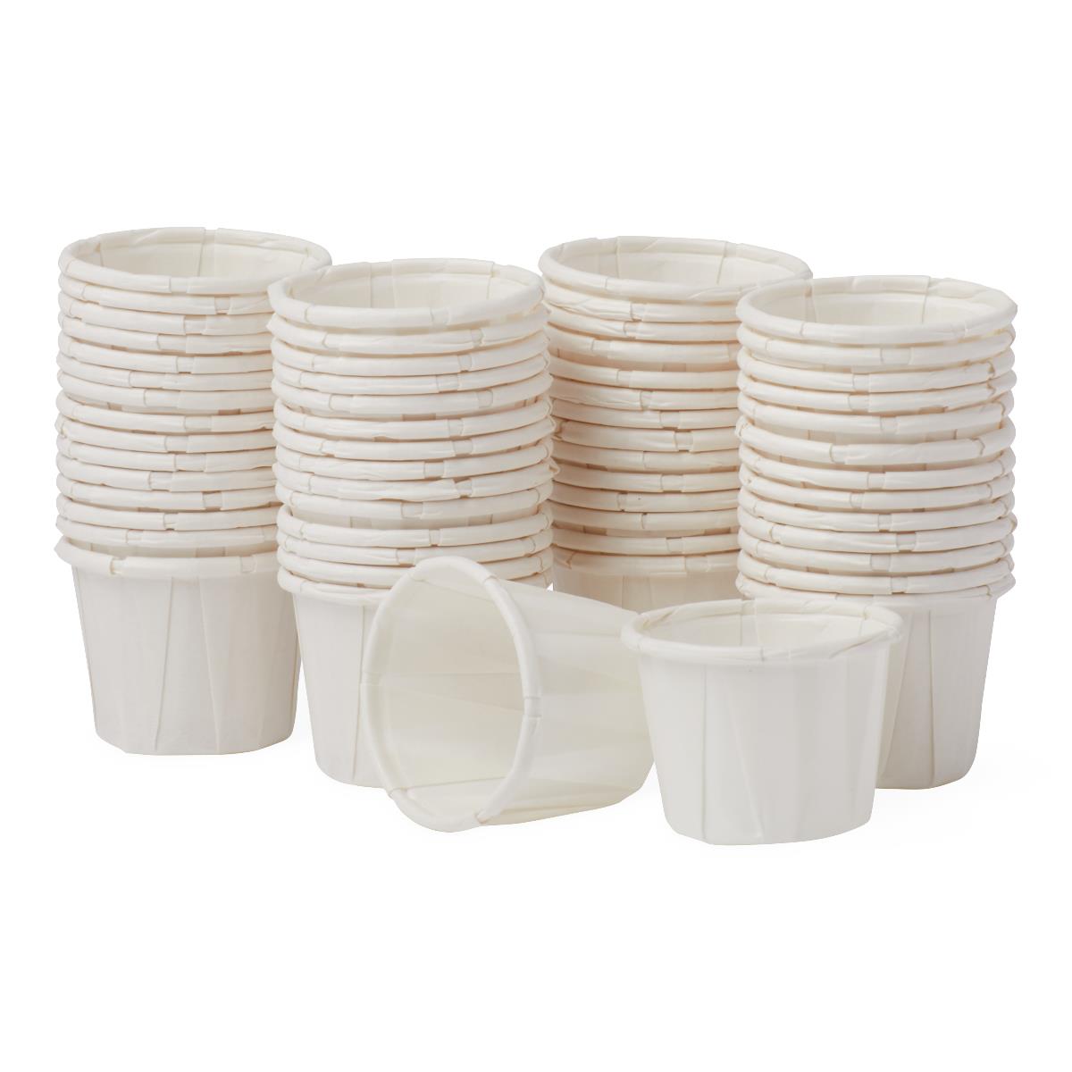 Disposable paper souffle cups in white with pleated sides, stacked in multiple columns with two cups shown upright in front