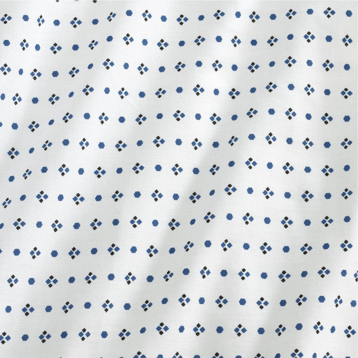 Patient gown fabric close-up showing white material with repeating blue dot and small diamond pattern