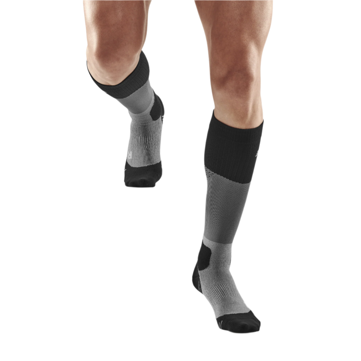 Compression hiking socks in black and gray worn on male legs, knee-high length with reinforced heel and toe zones