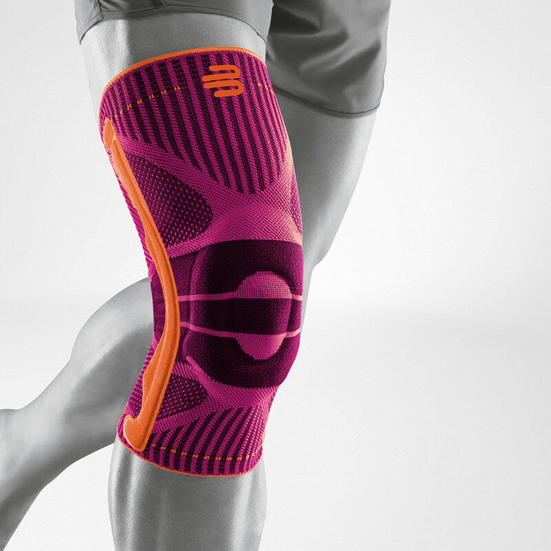 Knee support sleeve in pink and orange knit fabric with patella pad, worn on a bent knee