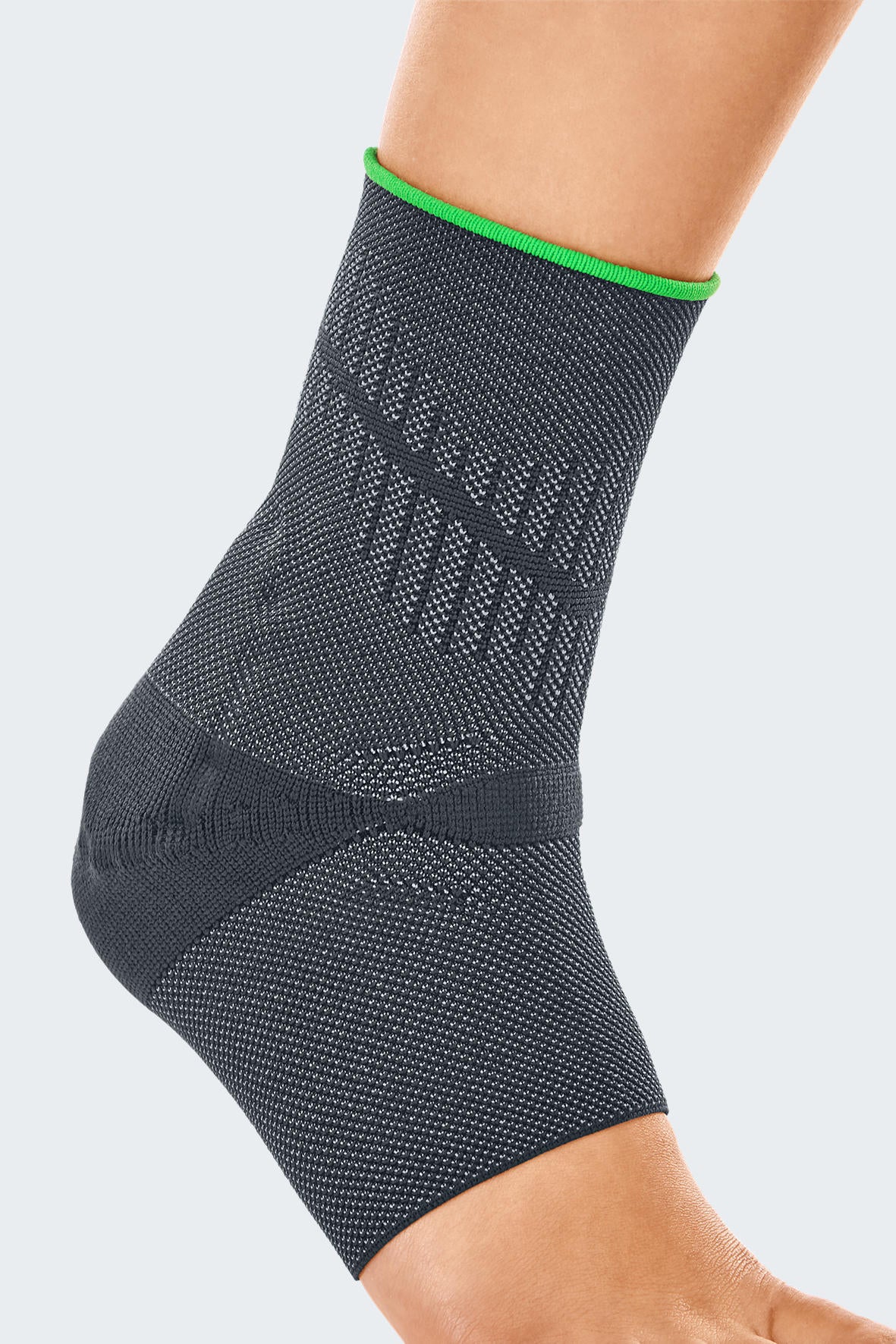 Ankle support brace in dark gray knit fabric with green trim and textured achilles strap, worn on a right foot