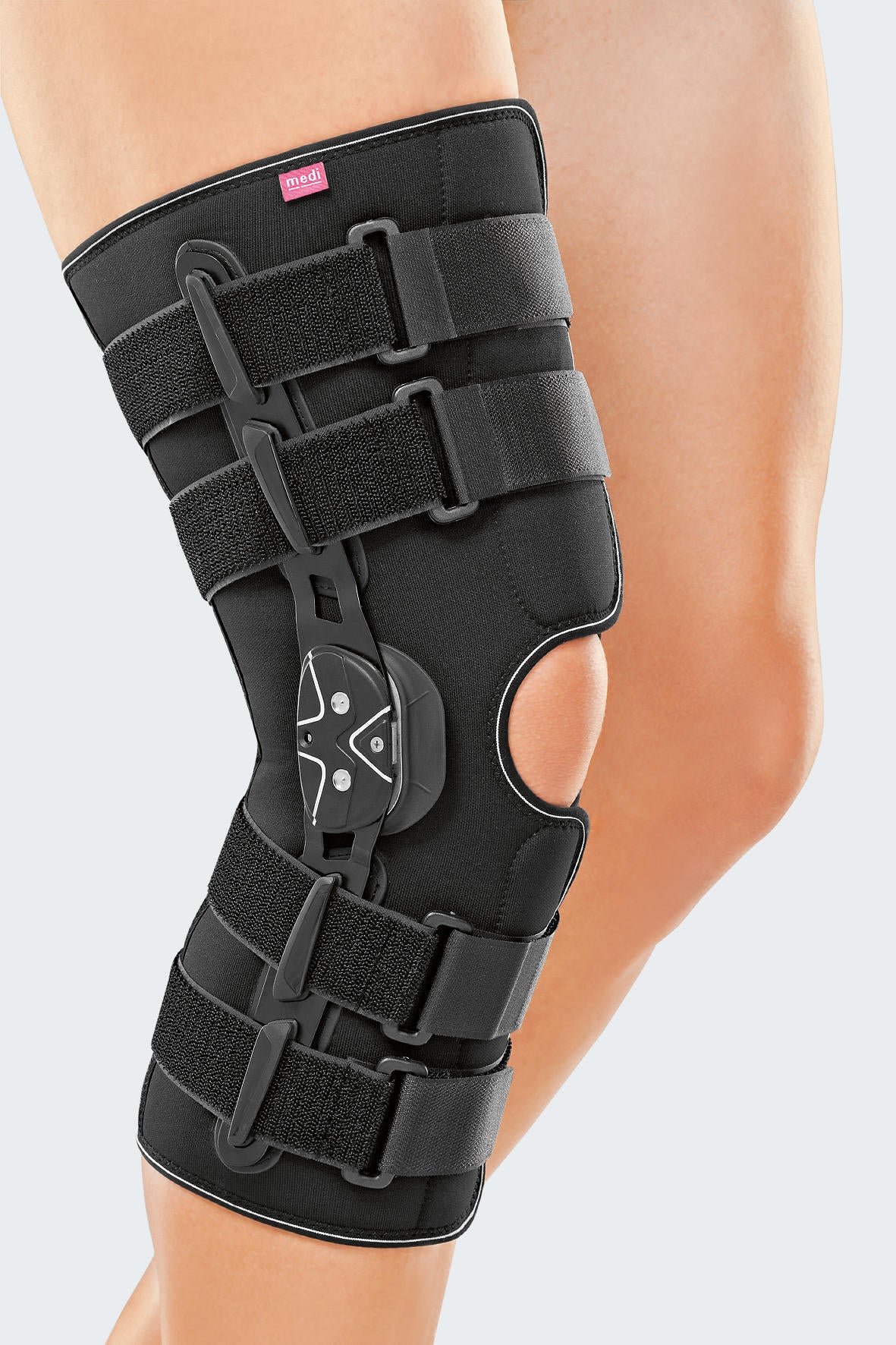 Protect.CO knee brace in black with hinged side stabilizers, adjustable straps, and open patella cutout, worn on a leg
