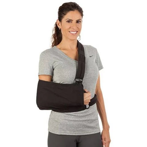 Shoulder immobilizer with padded black sling worn by smiling woman in gray t-shirt, shown from front view