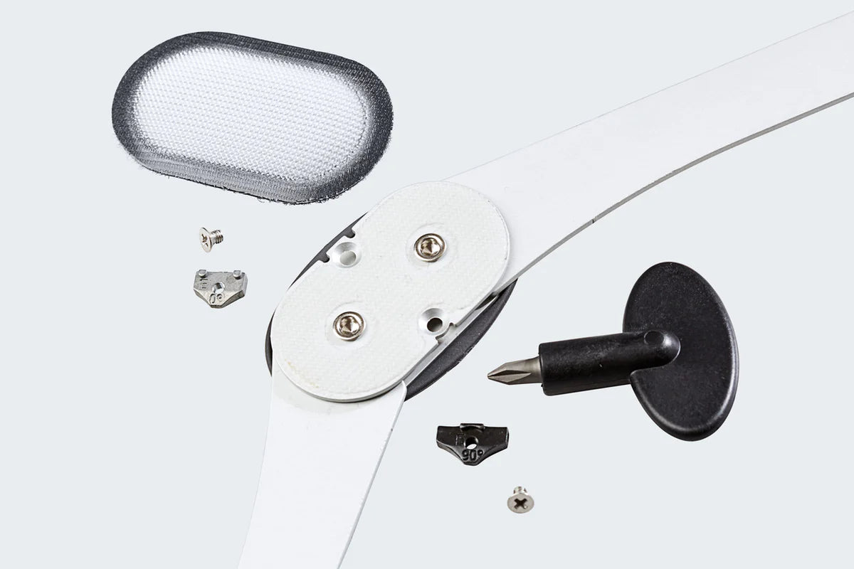 OA knee brace hinge assembly with screws, adjustment tool, hook-and-loop pad, and small hardware components laid out on