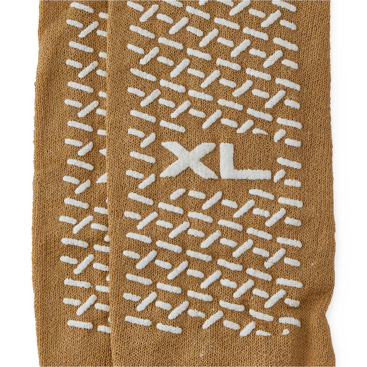 Non-skid patient slipper sock in tan with white rubber grip tread pattern and XL size marking on the sole
