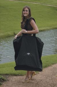 Wheelchair carrying case in black held open by a smiling woman standing outdoors near a pond