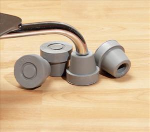 Quad cane tips in gray rubber, four pieces shown on wooden surface with cane leg visible above them