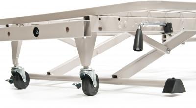 Hospital bed base with scissor-lift mechanism, swivel casters, and foot pedal controls on a white frame