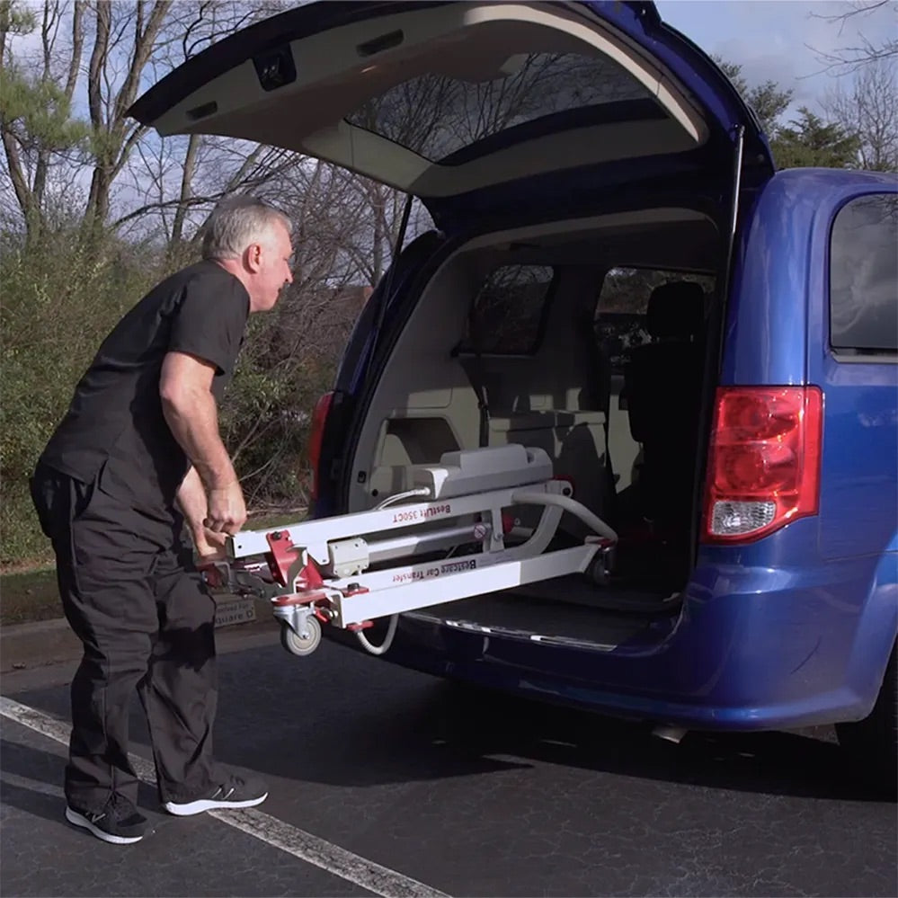 Car transfer mobile floor lift being loaded into the rear of a blue minivan by a man outdoors