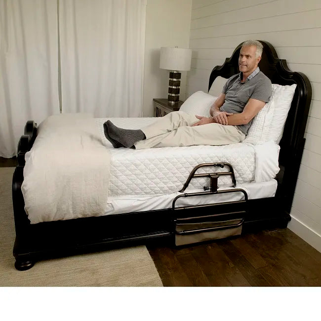 Bed rail with storage pouch mounted on a dark wood bed frame, man reclining with head elevated on adjustable mattress