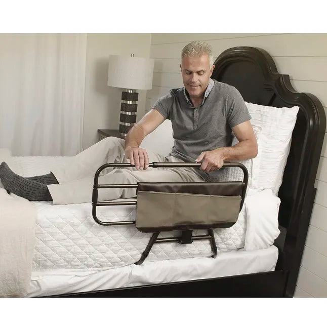 Bed rail with attached storage pouch secured to a home bed, shown with a man using the handle to assist sitting up