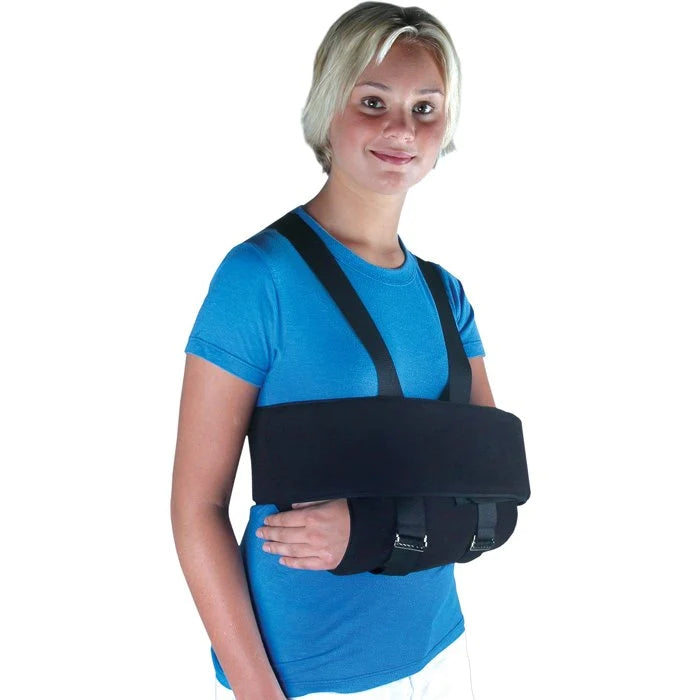 Shoulder sling and swathe immobilizer in black worn by a woman in a blue shirt, shown from a front-side angle