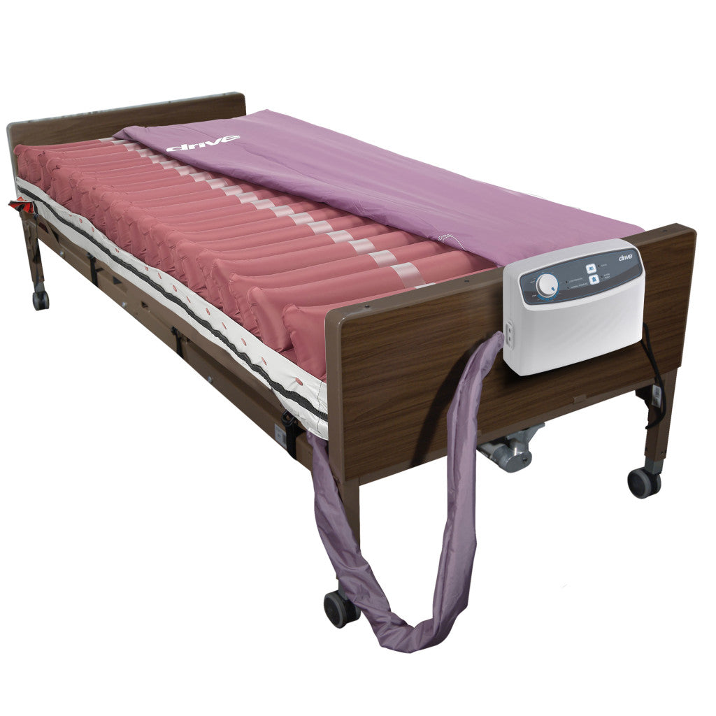 Alternating pressure mattress system with pink air cells on a hospital bed frame, electric pump unit mounted on footboard