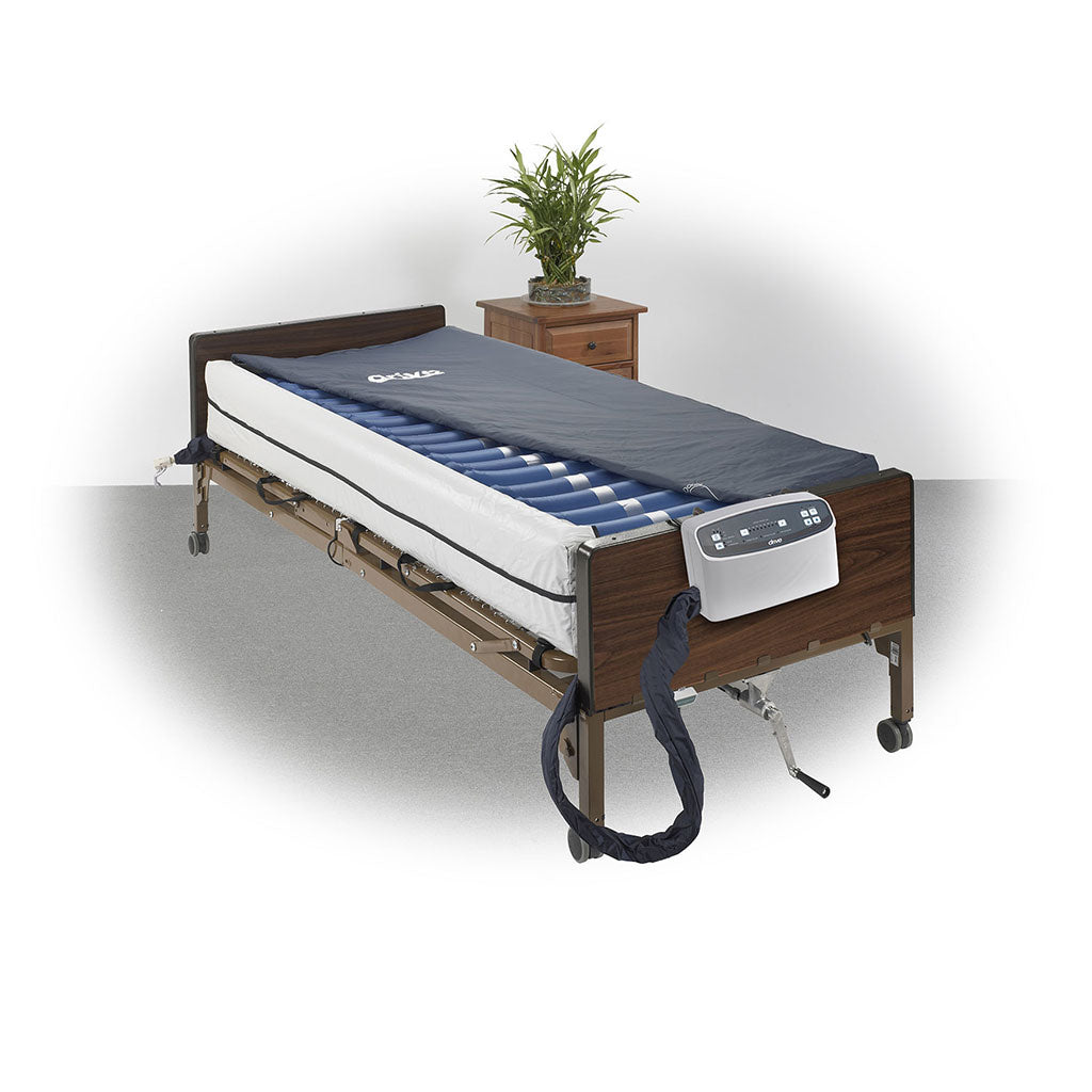 Alternating pressure mattress system with blue air cells and pump unit on a hospital bed with wood rails, nightstand in