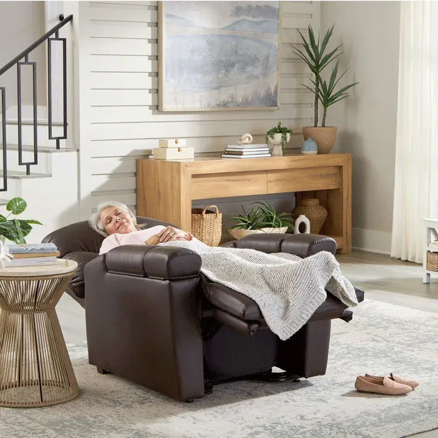 Power lift recliner in dark brown upholstery shown fully reclined with an elderly woman resting comfortably in a living room