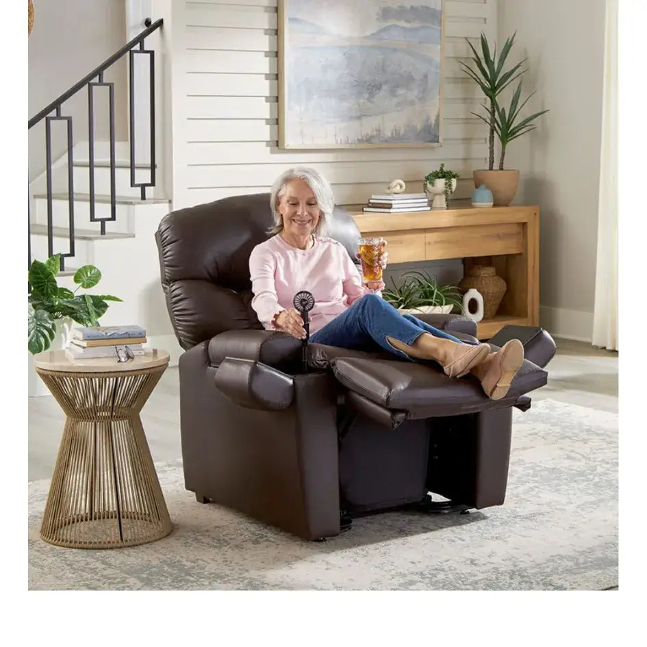 Power lift recliner chair in dark brown upholstery shown fully reclined with a smiling older woman holding a drink in a