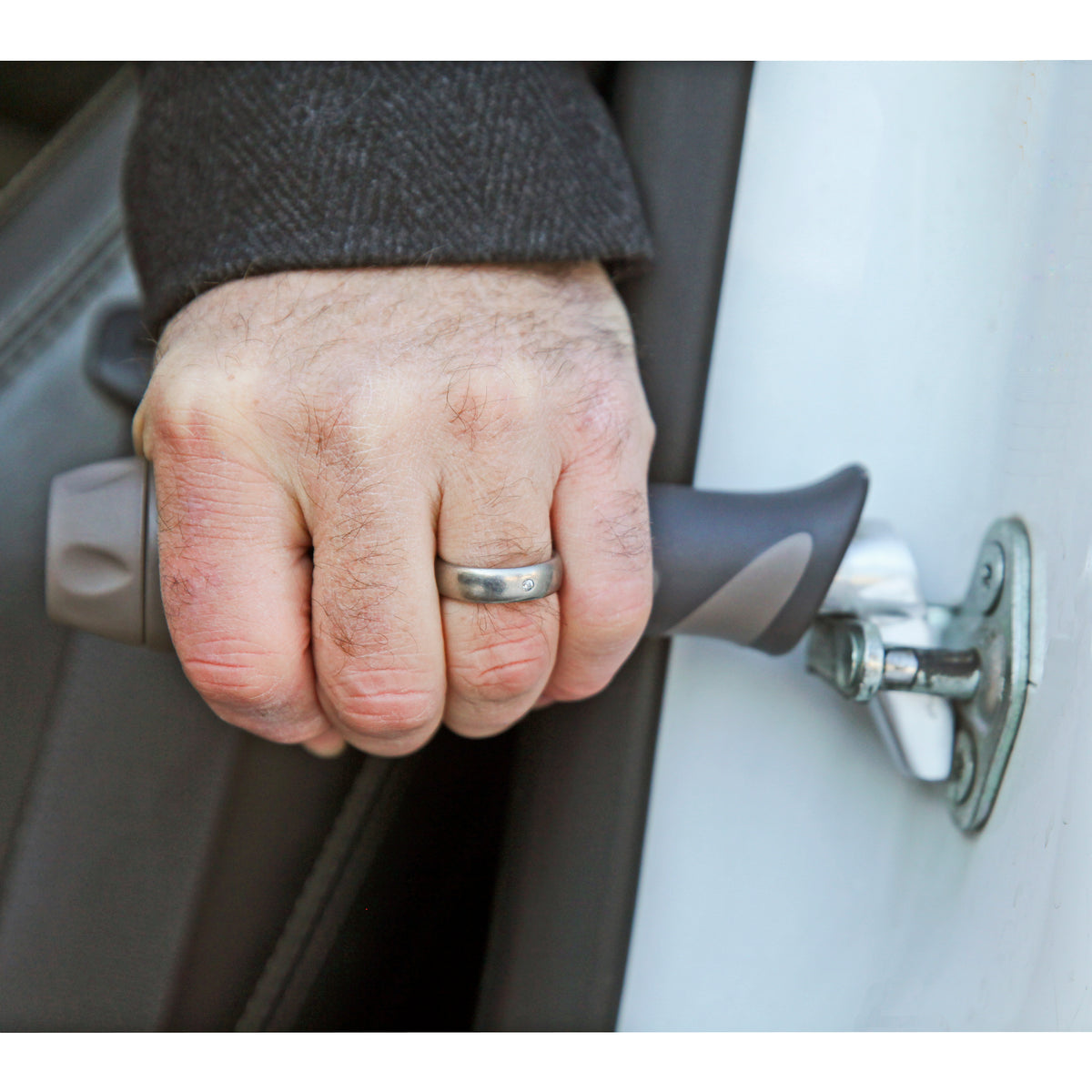 Car handle support bar inserted into vehicle door latch, gripped by a person's hand to assist with entering or exiting a