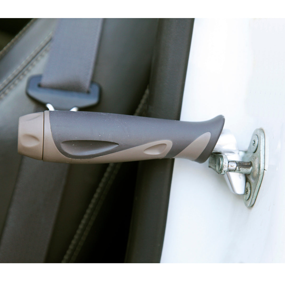 Car handle assist grip plugged into a vehicle door latch striker, shown beside a seat belt and leather car seat
