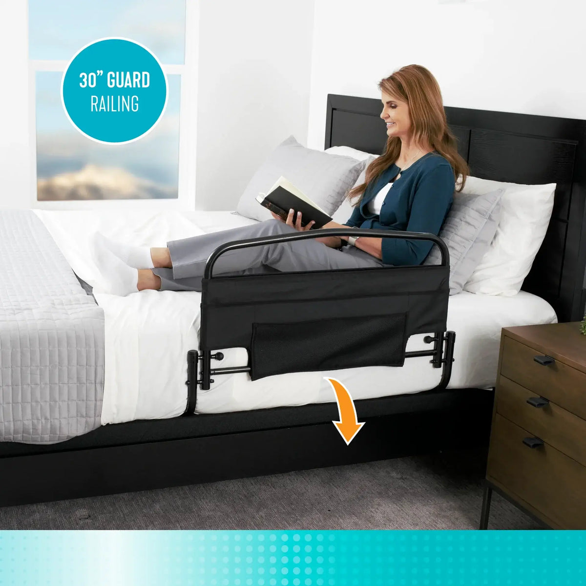 Bed rail with black padded pouch attached to side of bed, woman reading in background, arrow indicating under-mattress