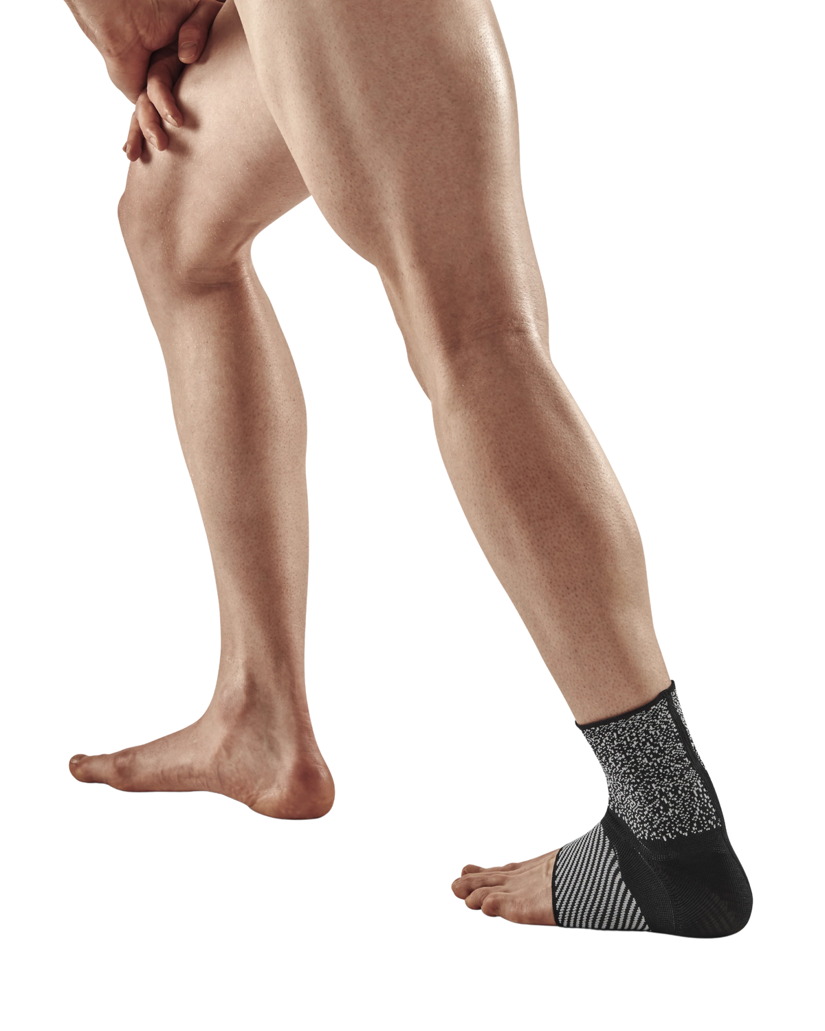 Ankle sleeve in black and gray knit fabric worn on a person's right foot and ankle, shown on white background