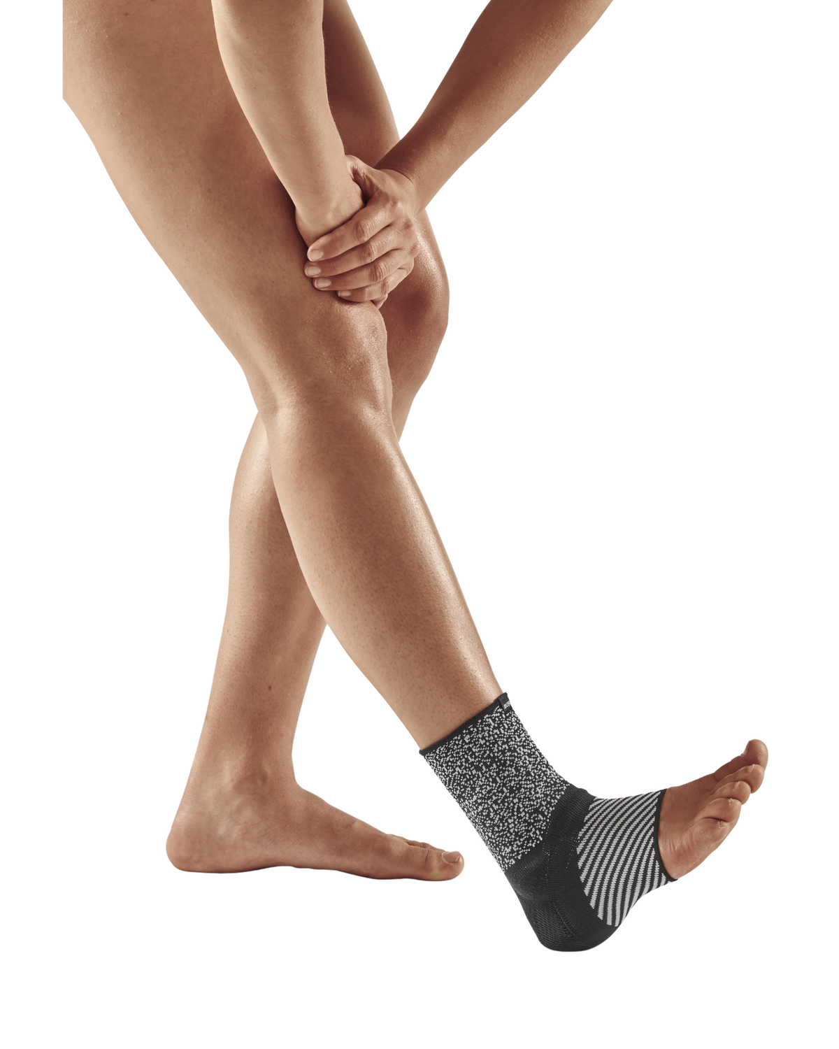 Ankle sleeve in black and gray knit fabric worn on a person's right foot, shown against a white background