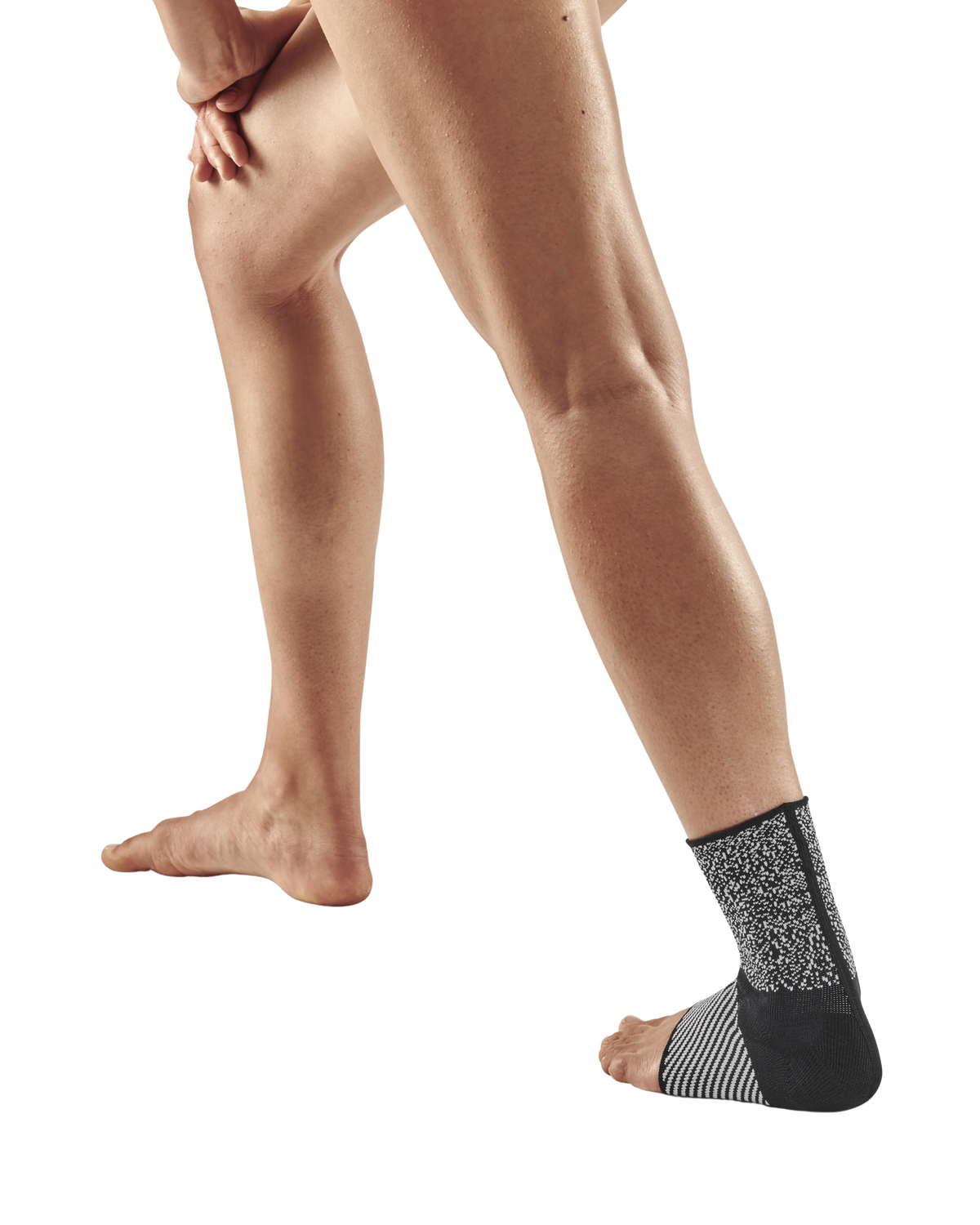 Ankle sleeve in black and gray knit fabric worn on a person's right ankle, shown against a white background