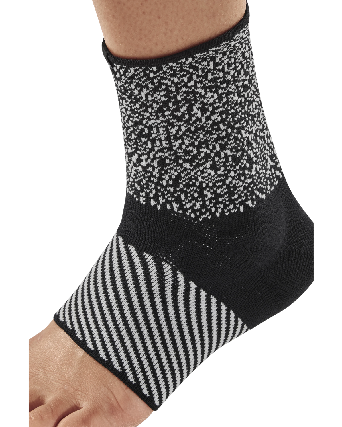 Ankle sleeve in black and white knit pattern worn on a foot, featuring textured upper and diagonal stripe design on lower