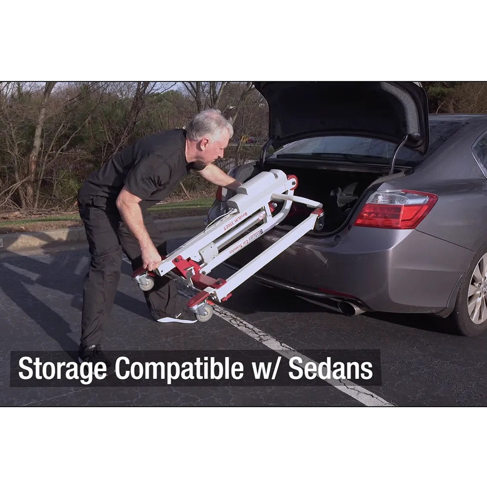 Car transfer mobile floor lift being loaded into a sedan trunk by a man in a parking lot, demonstrating compact storage