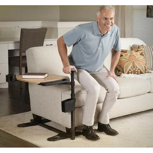 Couch stand assist rail with attached swivel tray table, shown supporting a man rising from a sofa in a living room